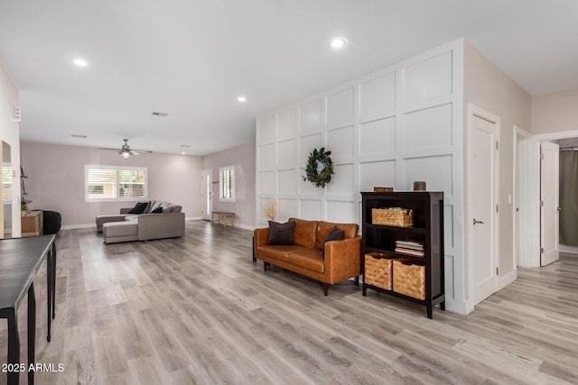 living room featuring recessed lighting, visible vents, a decorative wall, light wood-style flooring, and baseboards