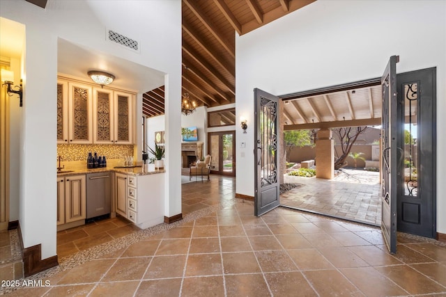 interior space with visible vents, backsplash, beam ceiling, high vaulted ceiling, and stainless steel dishwasher