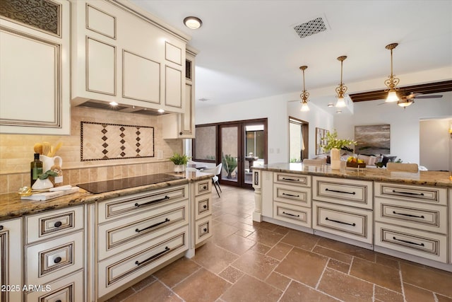 kitchen featuring black electric cooktop, cream cabinets, visible vents, and stone tile floors