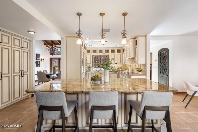 kitchen featuring cream cabinetry, a breakfast bar area, and stone tile floors