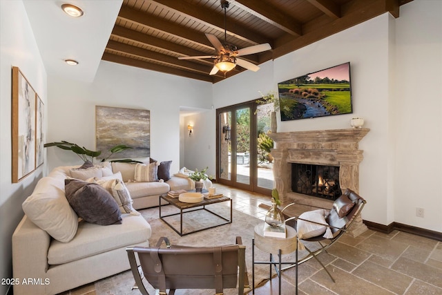 living area featuring baseboards, a fireplace, stone tile flooring, wood ceiling, and beamed ceiling