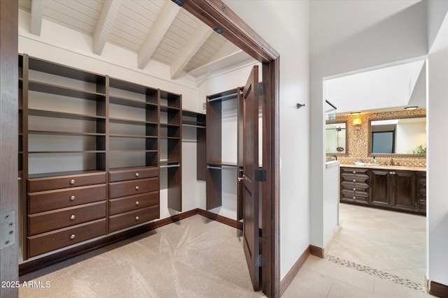 spacious closet featuring beam ceiling, light tile patterned floors, and a sink