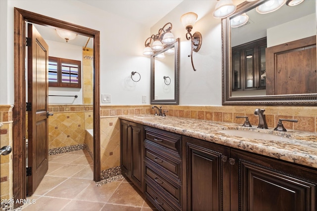 bathroom with a sink, tile walls, wainscoting, and tile patterned floors