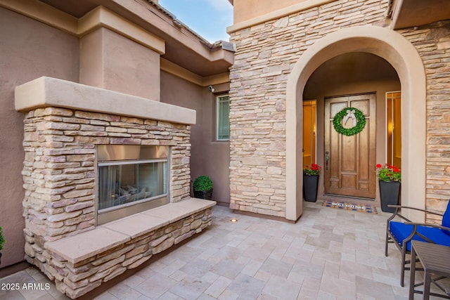 3654 E San Pedro Pl, Chandler, AZ 85249 - view of exterior entry featuring an outdoor stone fireplace, stone siding, and stucco siding