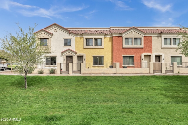 view of front of home with a front lawn, a tiled roof, a fenced front yard, and stucco siding