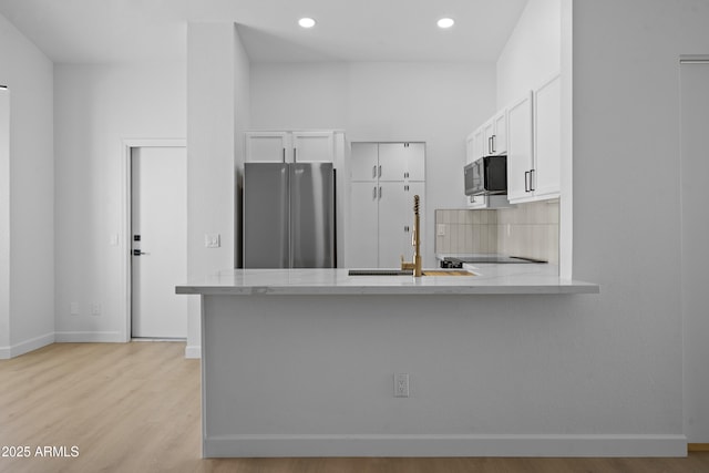 1881 E Kerby Farms Rd, Chandler, AZ 85249 - kitchen featuring freestanding refrigerator, a peninsula, light stone counters, white cabinets, and light wood-style flooring