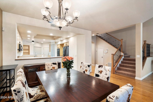 dining area featuring ceiling fan with notable chandelier and light wood-type flooring