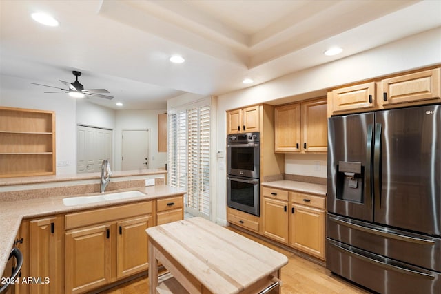 kitchen with appliances with stainless steel finishes, sink, ceiling fan, light brown cabinets, and light wood-type flooring