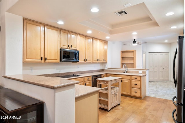 kitchen featuring black appliances, light brown cabinetry, and kitchen peninsula