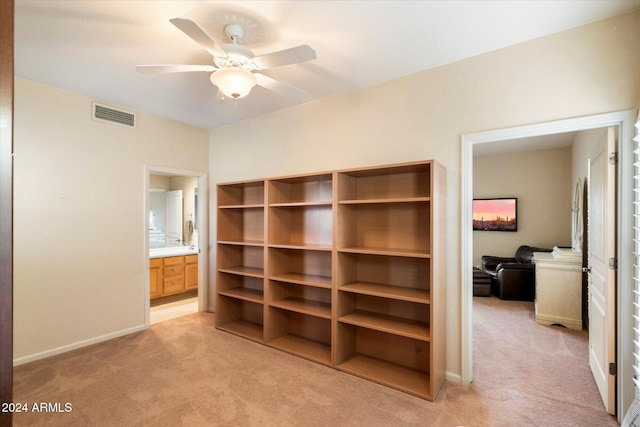 interior space featuring ceiling fan, light colored carpet, and ensuite bath