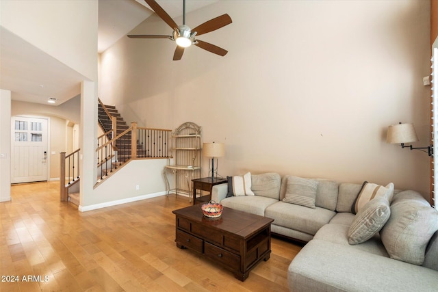 living room with hardwood / wood-style floors, a towering ceiling, and ceiling fan