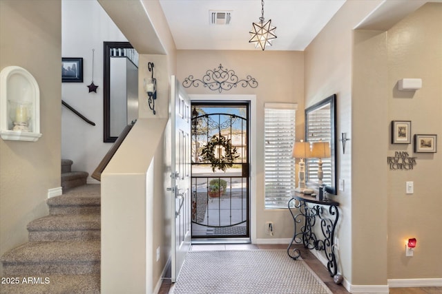 entrance foyer featuring stairs, visible vents, and baseboards