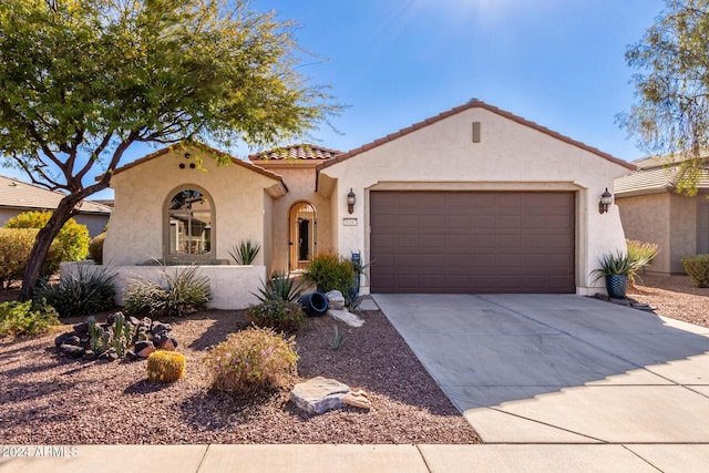 mediterranean / spanish-style home with concrete driveway, a tile roof, an attached garage, and stucco siding