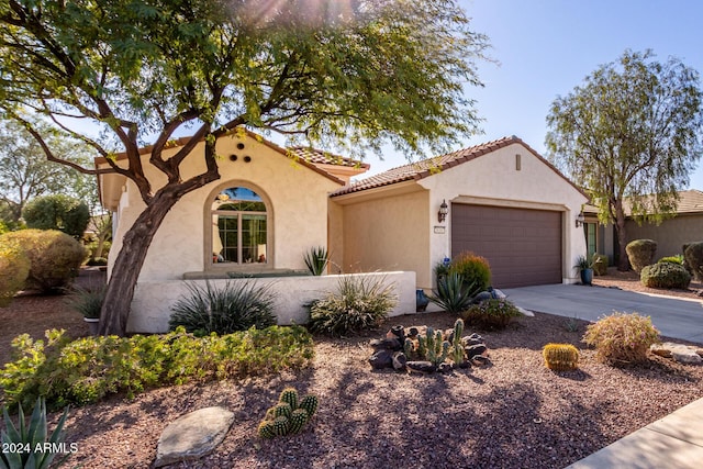 mediterranean / spanish-style house with an attached garage, driveway, a tile roof, and stucco siding