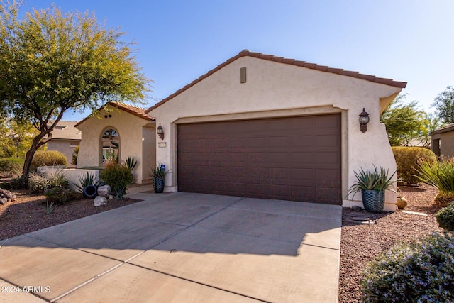 mediterranean / spanish house with driveway, a tiled roof, an attached garage, and stucco siding