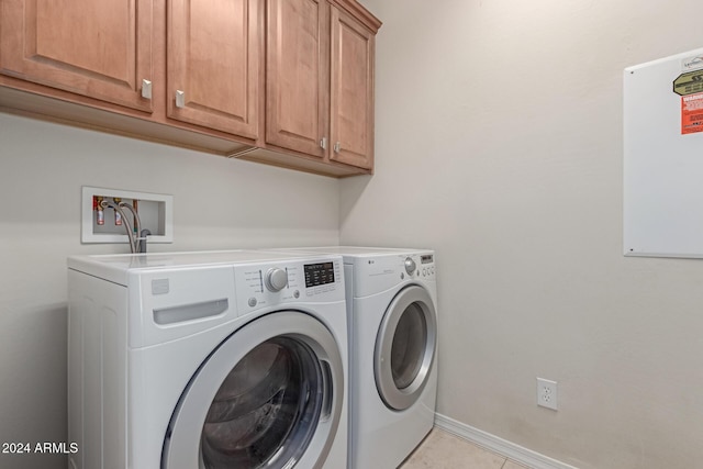 clothes washing area with washer and dryer, cabinet space, baseboards, and light tile patterned floors