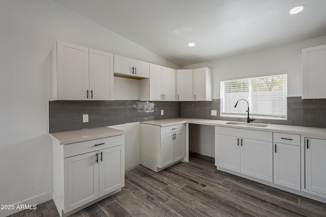 kitchen with sink, white cabinetry, vaulted ceiling, tasteful backsplash, and dark hardwood / wood-style floors