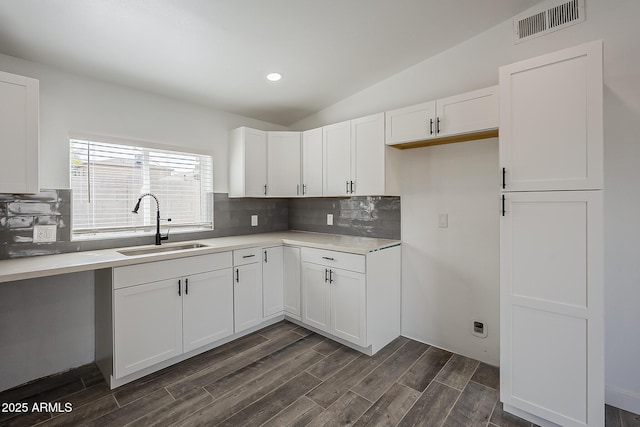 kitchen featuring sink, white cabinetry, and lofted ceiling