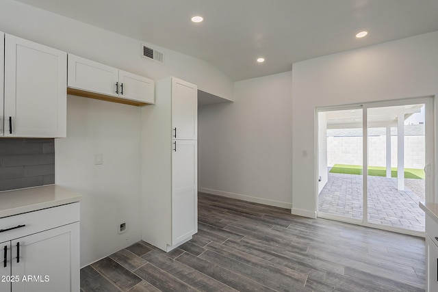 kitchen featuring dark wood-type flooring, backsplash, and white cabinetry