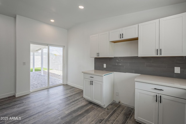 kitchen featuring vaulted ceiling, white cabinets, tasteful backsplash, and dark wood-type flooring