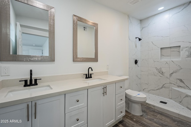 bathroom featuring toilet, vanity, tiled shower, and hardwood / wood-style floors