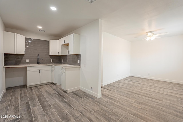 kitchen featuring sink, white cabinets, light wood-type flooring, ceiling fan, and decorative backsplash