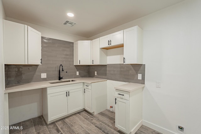 kitchen featuring sink, white cabinetry, hardwood / wood-style floors, and tasteful backsplash