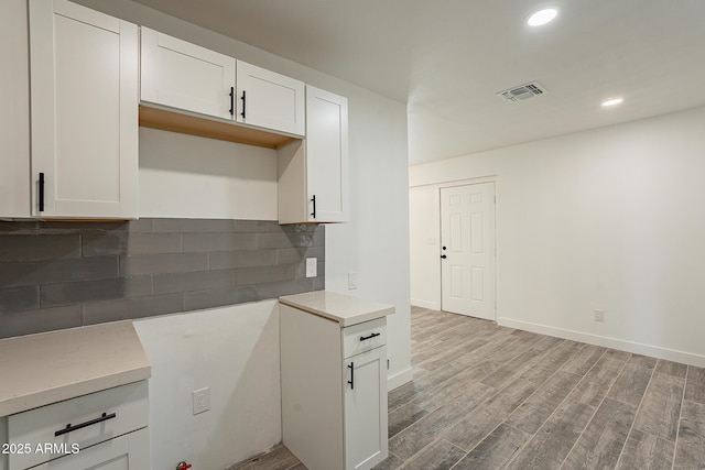 kitchen featuring white cabinets, light hardwood / wood-style flooring, and backsplash