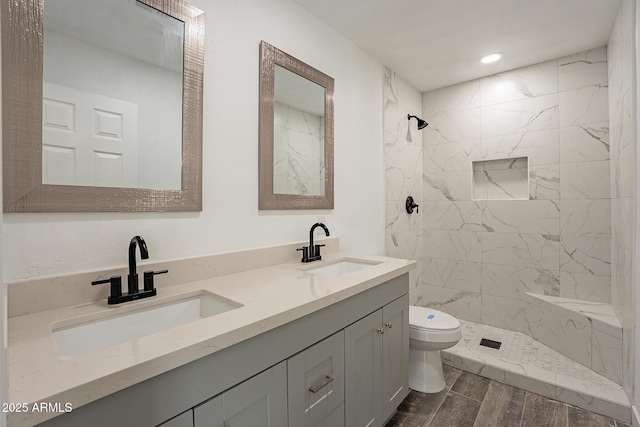 bathroom featuring toilet, vanity, and tiled shower