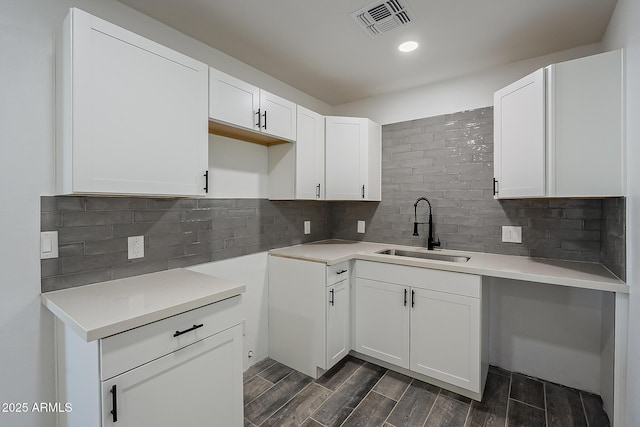 kitchen featuring sink, white cabinets, and backsplash