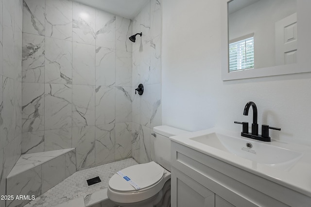 bathroom with a tile shower, vanity, and toilet