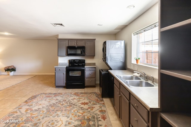 1330 E Monte Vista Rd, Phoenix, AZ 85006 - kitchen with black appliances, a sink, stacked washer and clothes dryer, light tile patterned floors, and light countertops