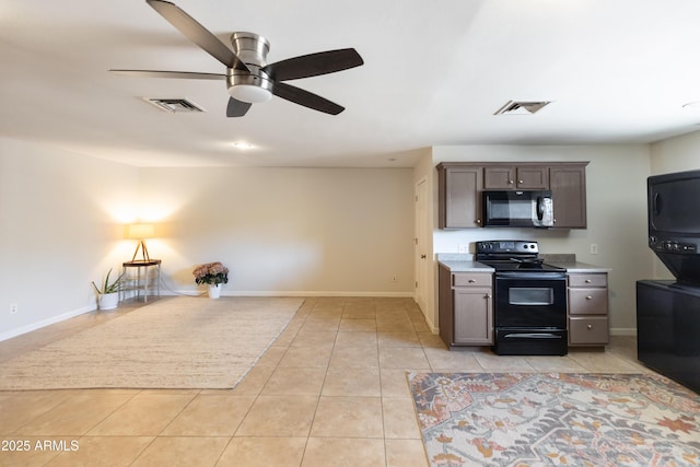 1330 E Monte Vista Rd, Phoenix, AZ 85006 - kitchen featuring black appliances, estacked washer and dryer, light tile patterned flooring, and light countertops