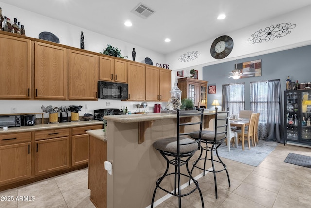 kitchen featuring a breakfast bar area, ceiling fan, stove, a center island, and light tile patterned flooring