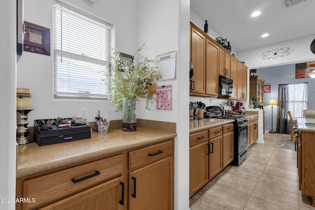 kitchen with a wealth of natural light, light tile patterned floors, and black appliances