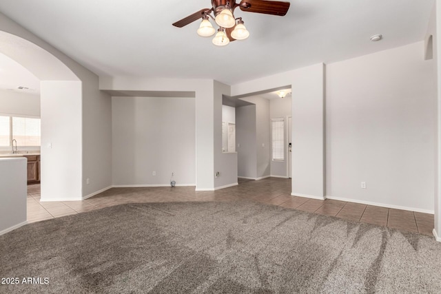 18719 E Pelican Ct, Queen Creek, AZ 85142 - tiled spare room with a ceiling fan, carpet floors, arched walkways, a sink, and baseboards