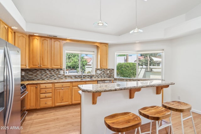 7734 E Rose Ln, Scottsdale, AZ 85250 - kitchen featuring stainless steel appliances, a sink, light wood-style floors, decorative backsplash, and a breakfast bar area