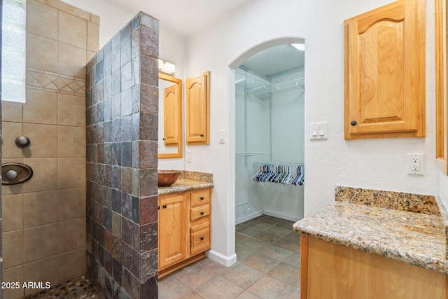 7734 E Rose Ln, Scottsdale, AZ 85250 - bathroom with tile patterned flooring, a tile shower, and vanity
