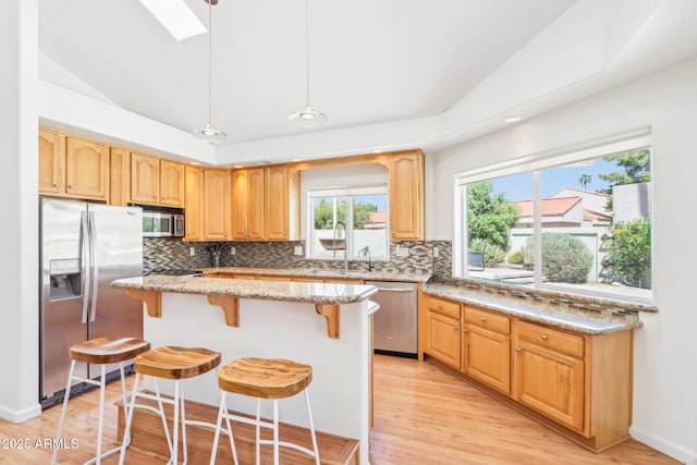 7734 E Rose Ln, Scottsdale, AZ 85250 - kitchen featuring light stone counters, appliances with stainless steel finishes, a breakfast bar area, and decorative backsplash