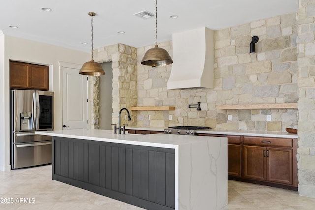 kitchen featuring decorative light fixtures, sink, custom exhaust hood, stove, and stainless steel refrigerator with ice dispenser