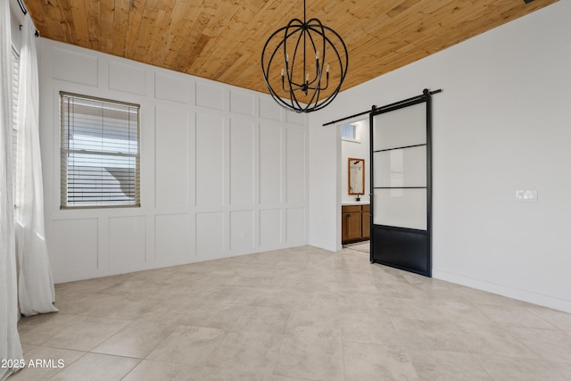 empty room featuring a barn door, a notable chandelier, and wood ceiling