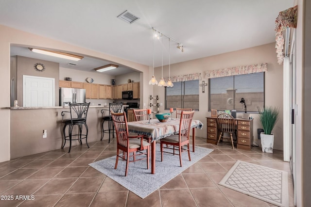 dining space featuring tile patterned flooring, rail lighting, and visible vents