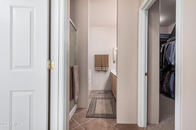 full bath featuring a spacious closet, vanity, and tile patterned flooring