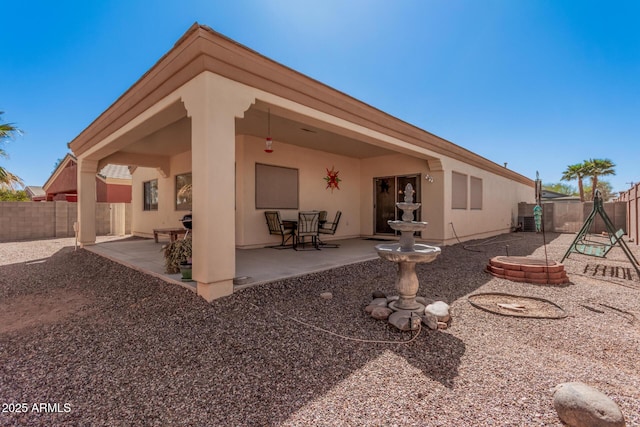 rear view of house with stucco siding, a fenced backyard, and a patio area