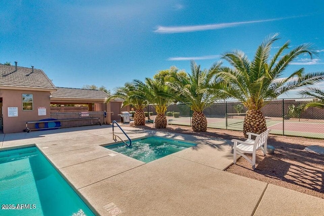 pool with a community hot tub, a patio, and fence