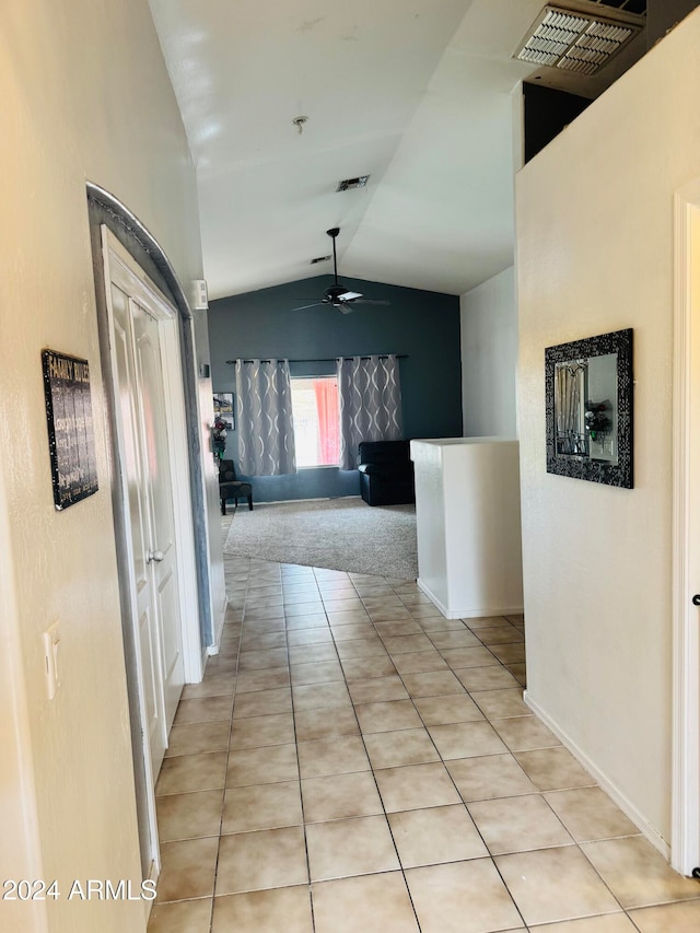 hall featuring light tile patterned floors and lofted ceiling