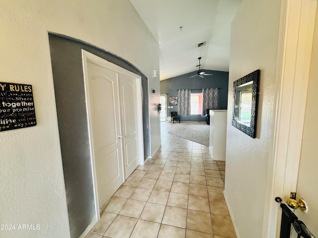 hallway featuring light tile patterned flooring and vaulted ceiling