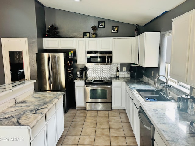 kitchen featuring appliances with stainless steel finishes, vaulted ceiling, sink, light tile patterned floors, and white cabinetry