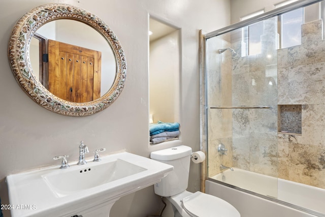 full bathroom featuring enclosed tub / shower combo, sink, and toilet