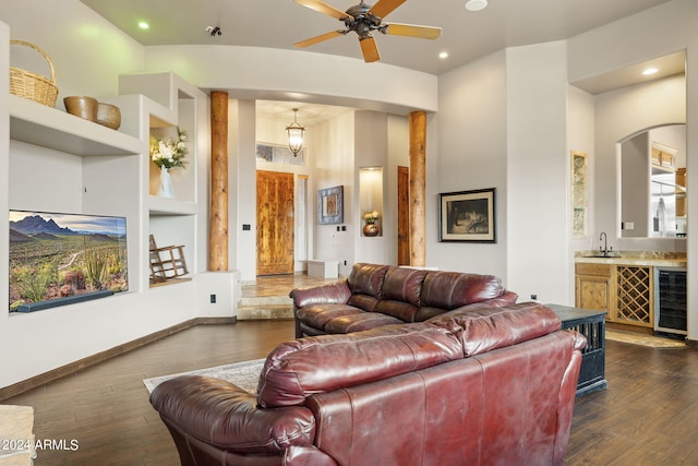 living room featuring ceiling fan, dark wood-type flooring, beverage cooler, sink, and built in shelves